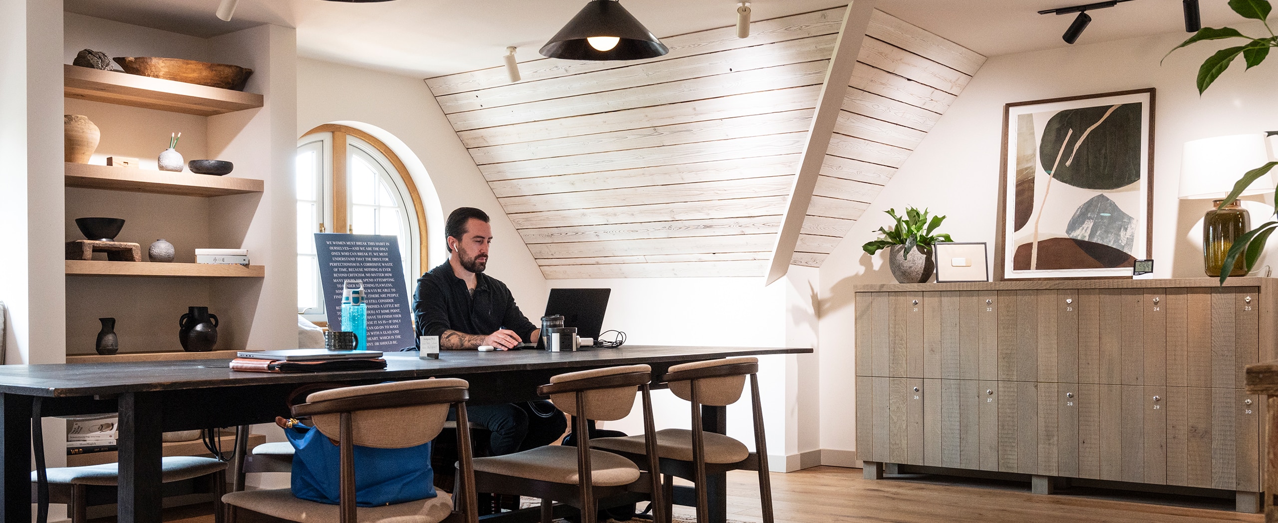 Man working on his laptop at a table in a co-working space