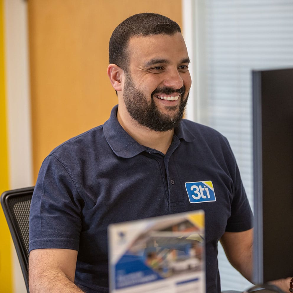 Man sitting at a desk looking at a computer screen and smiling